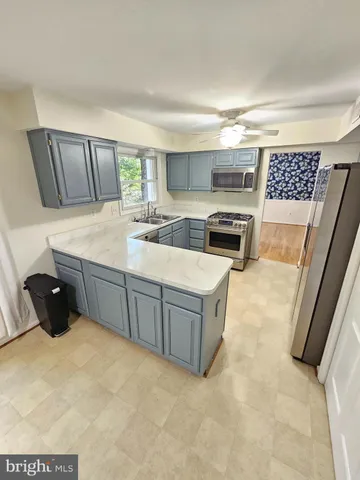 a kitchen with stainless steel appliances a sink a stove a refrigerator cabinets and a window