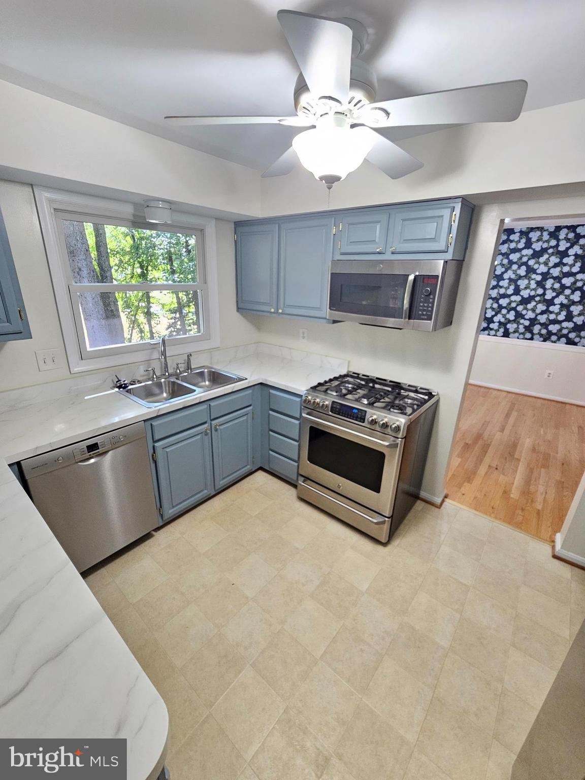 11321 Classical Lane Silver Spring, MD 20901 - Photo 19 of 66 a kitchen with stainless steel appliances a sink a stove a refrigerator cabinets and a window
