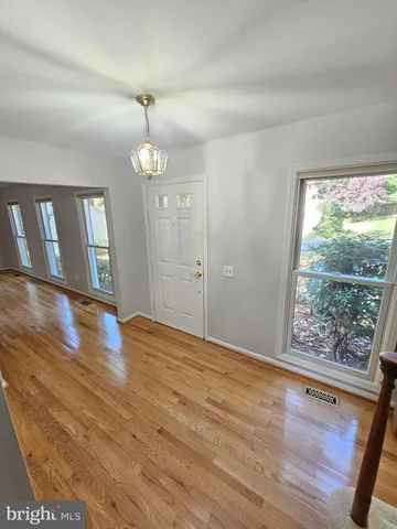 a view of an empty room with wooden floor and fan