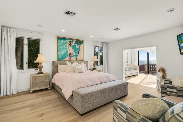 a spacious bedroom with a bed a couch and large window