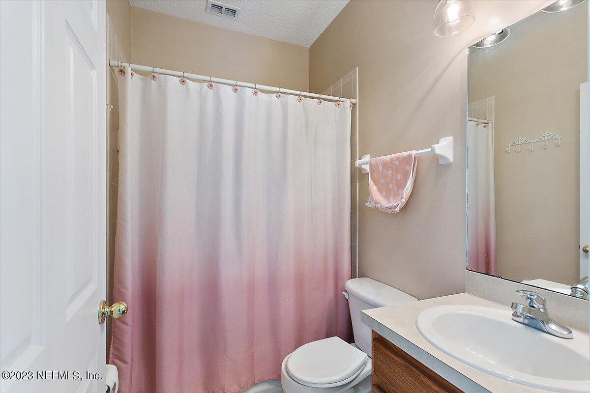 776 Constitution Place Macclenny, FL 32063 - Photo 18 of 30 a bathroom with a sink a toilet a mirror and shower curtain