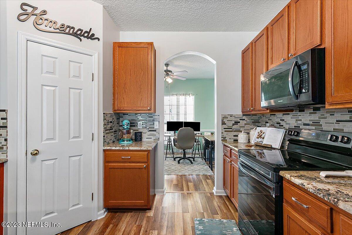776 Constitution Place Macclenny, FL 32063 - Photo 9 of 30 a kitchen with stainless steel appliances a stove a sink cabinets and a wooden floor