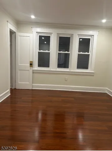 a view of an empty room with wooden floor and windows