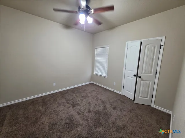 an empty room with a fan & a window