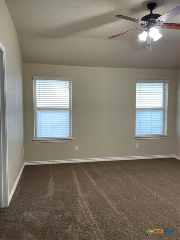 en empty room with windows and chandelier fan