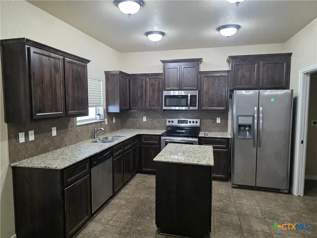 a kitchen with a refrigerator sink and cabinets