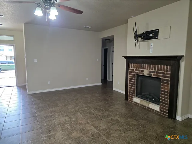 a living room with a fireplace furniture a ceiling fan and a window