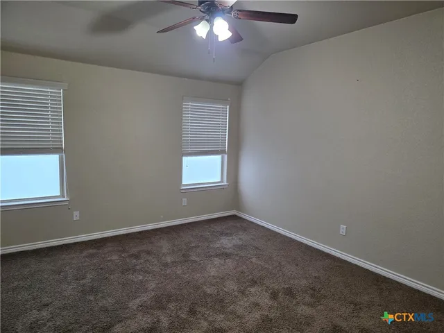 en empty room with windows and chandelier fan