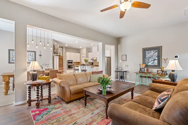 a living room with furniture kitchen view and a wooden floor