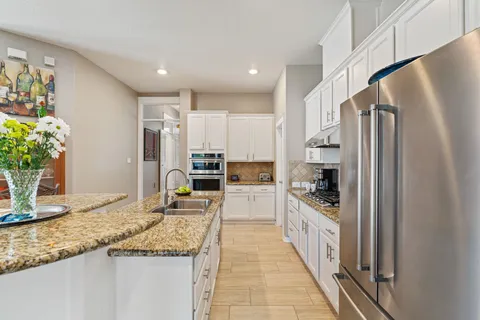 a large kitchen with granite countertop a large counter top stainless steel appliances and a counter space