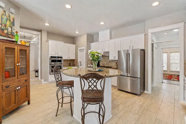 a kitchen with stainless steel appliances a refrigerator a stove a dining table and chairs