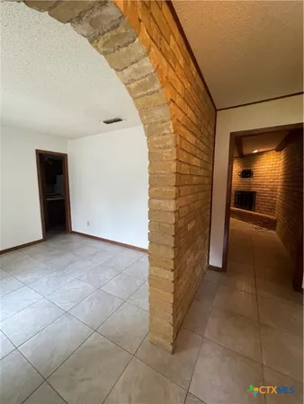 a view of an empty room and kitchen space with a sink