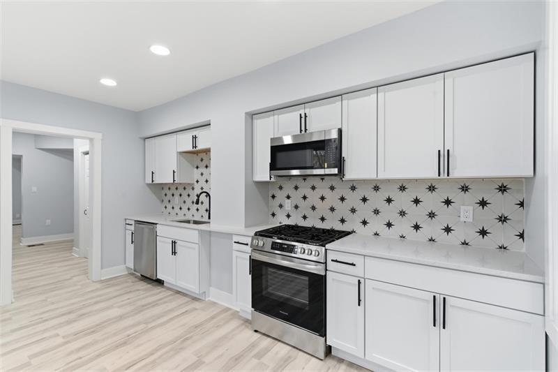 1150 Goettmann Street Pittsburgh, PA 15212 - Photo 3 of 36 a kitchen with granite countertop a sink stove and microwave