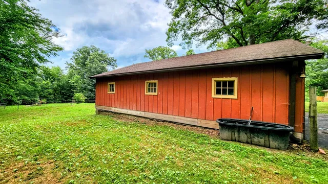 a backyard of a house with yard plants and large tree