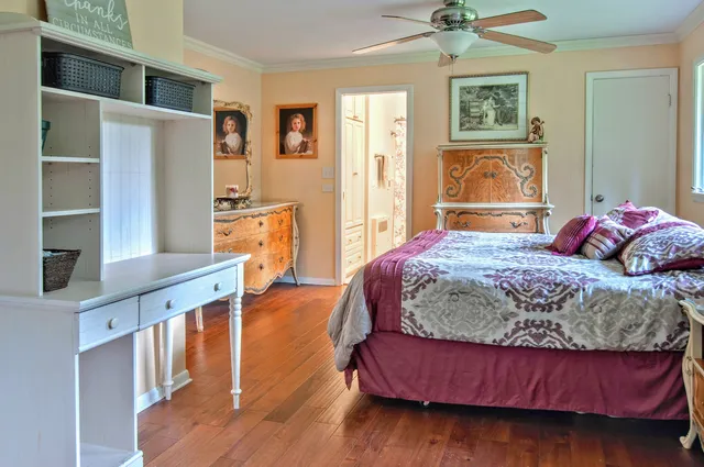 a bedroom with a bed and a dresser with wooden floor