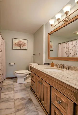 a bathroom with a granite countertop sink mirror vanity and toilet