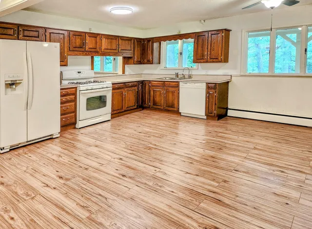 a kitchen with stainless steel appliances granite countertop a stove a sink dishwasher and a refrigerator with wooden floor