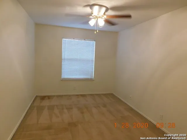 an empty room with a window and a chandelier fan