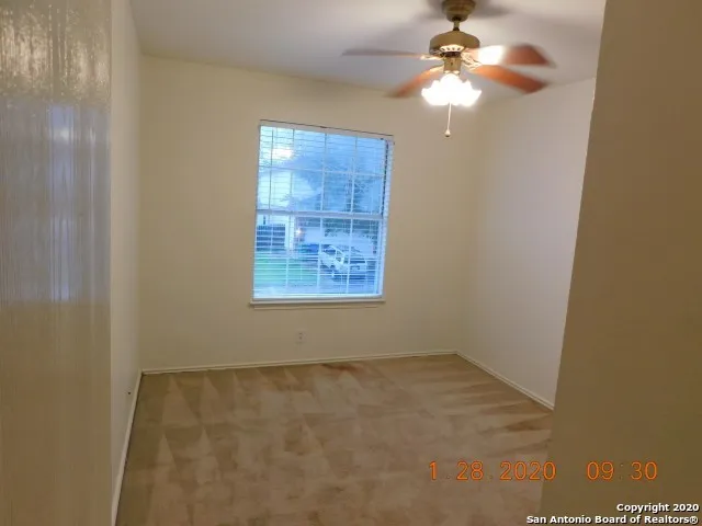 an empty room with windows and fan