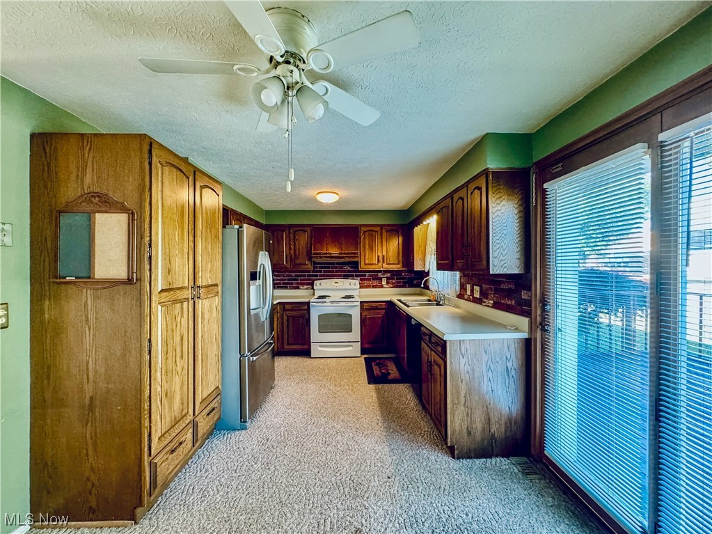 304 Stone Road Belpre, OH 45714 - Photo 14 of 34 Kitchen with light carpet, stainless steel fridge, ceiling fan, sink, and white electric range