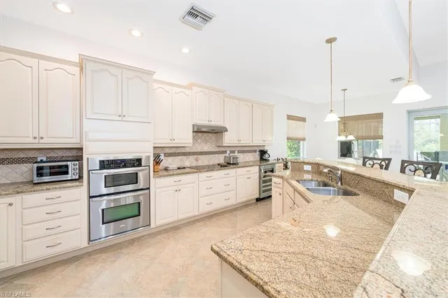 a large kitchen with granite countertop a sink a counter space appliances and cabinets