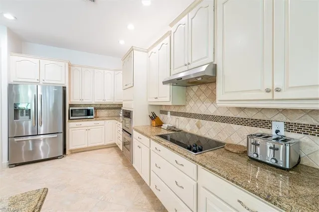 a kitchen with granite countertop a sink stainless steel appliances and white cabinets