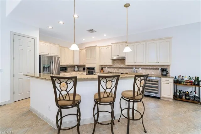 a kitchen with stainless steel appliances a dining table chairs and white cabinets