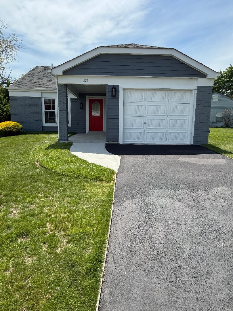 379 Larchmont Court Ridge, NY 11961 - Photo 17 of 17 a front view of a house with a yard and garage