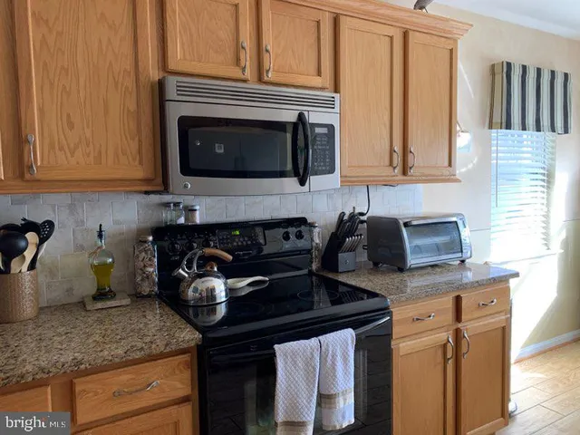 a kitchen with granite countertop a sink a stove and cabinets