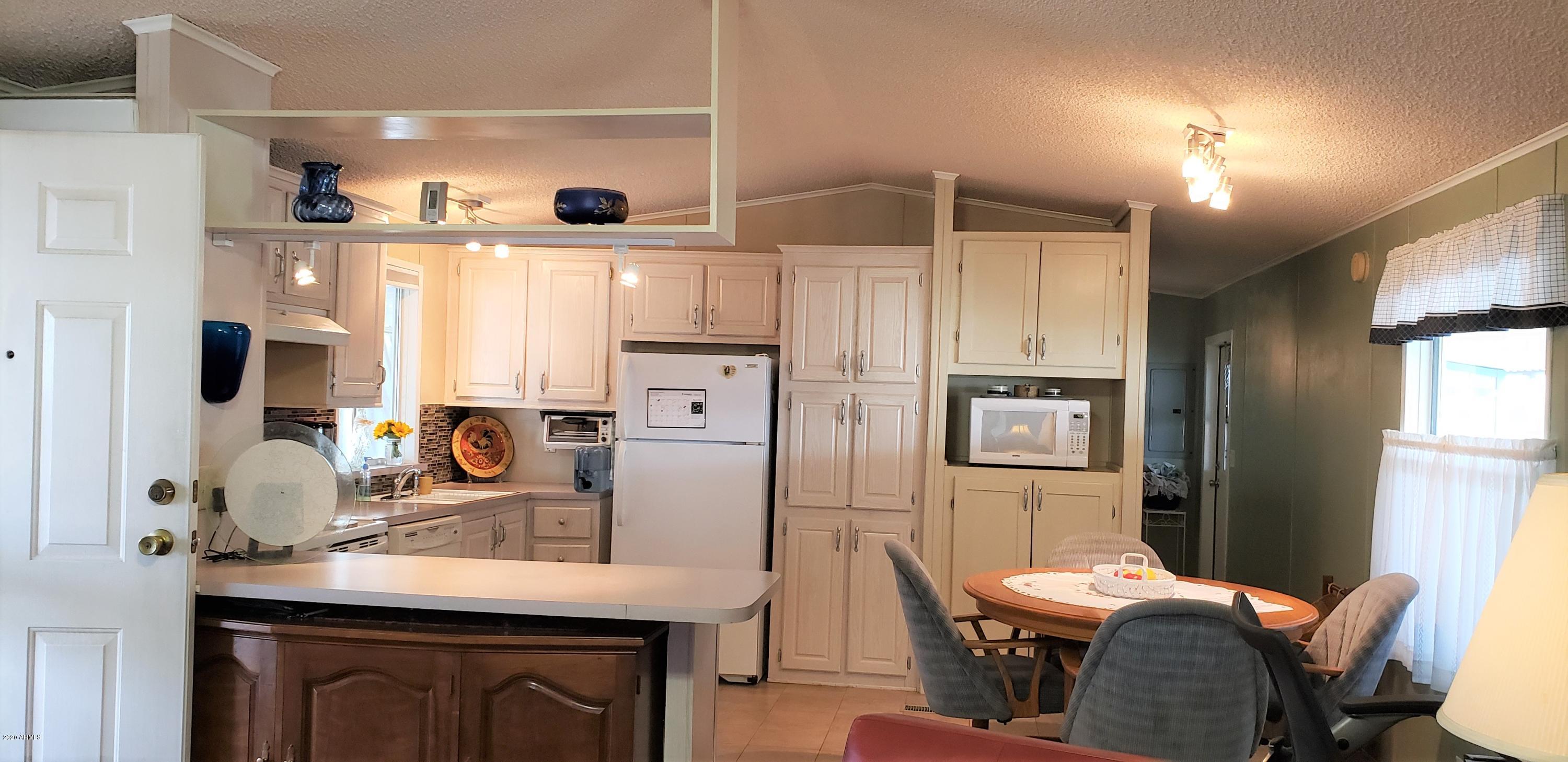 301 South Signal Butte Road, Unit 226 Apache Junction, AZ 85120 - Photo 10 of 42 a kitchen with stainless steel appliances kitchen island granite countertop a refrigerator a stove a sink dishwasher with a dining table and chairs