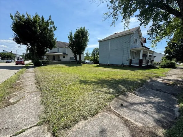 a front view of a house with a garden and trees