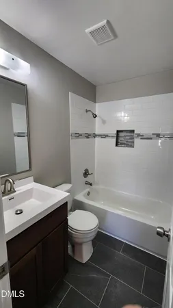 a bathroom with a bathtub shower sink vanity and toilet
