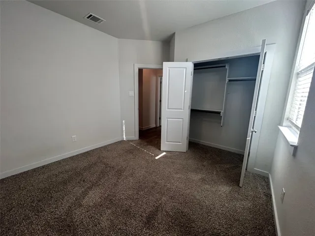 a view of an empty room with window and closet area