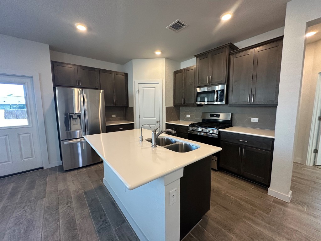 212 Whisper Rill Drive Hutto, TX 78634 - Photo 5 of 25 a kitchen with stainless steel appliances granite countertop a refrigerator a sink a stove a microwave and wooden floor