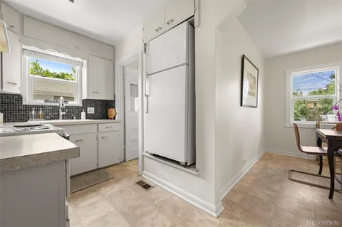 a kitchen with a sink a refrigerator a window and cabinets
