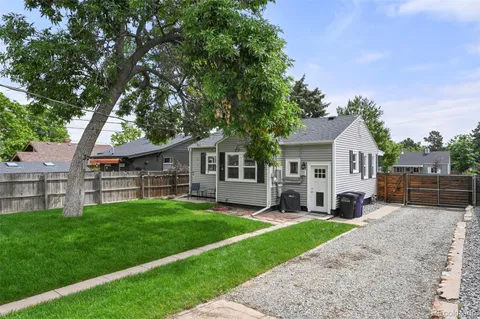 a view of house with a big yard and large trees