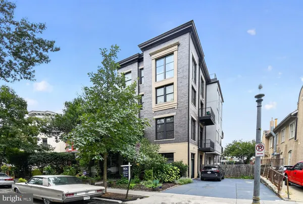 a front view of a building with street view and trees