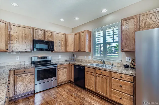 a kitchen with stainless steel appliances granite countertop a stove a sink dishwasher a refrigerator and a microwave oven with wooden cabinets