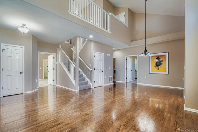 a view of an empty room with wooden floor fireplace and a window