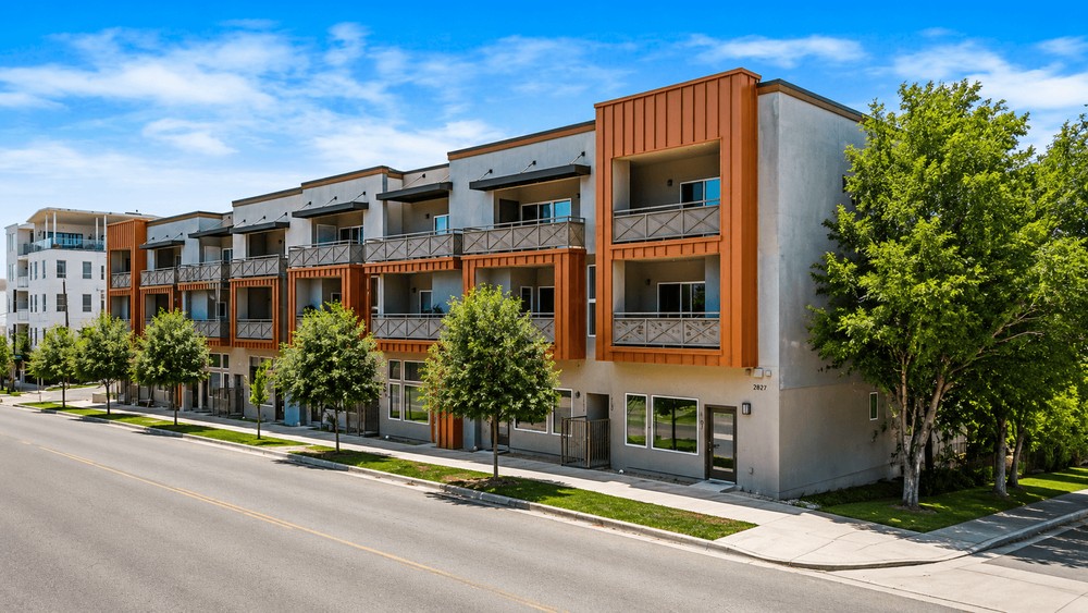 Modern multi-story building featuring balconies with decorative railings and sunshades