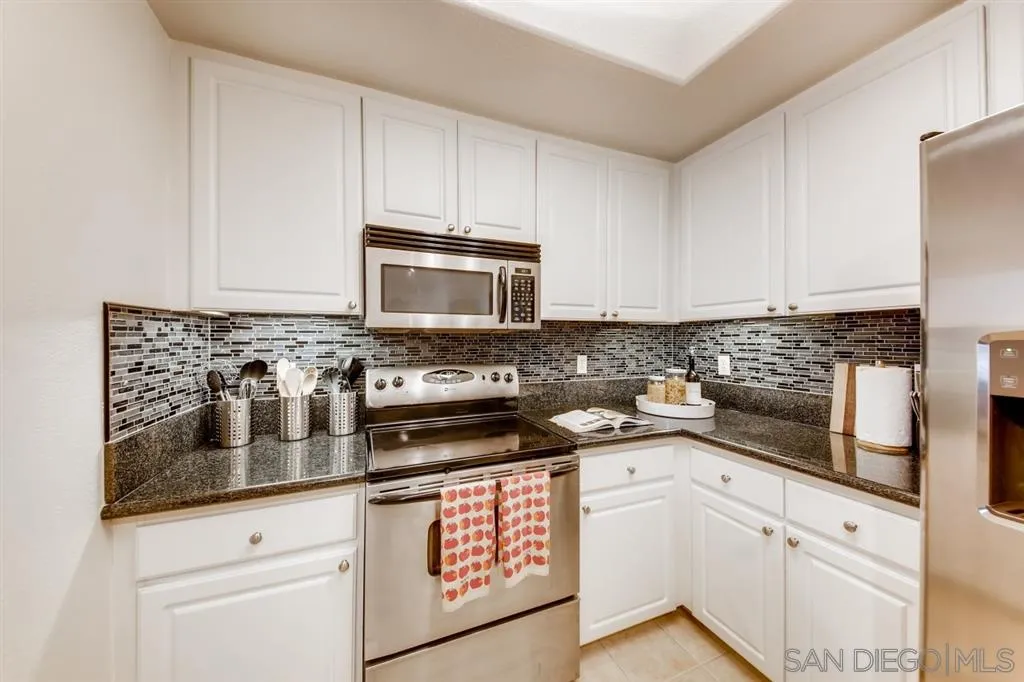 9263 Regents Road, Unit B203 La Jolla, CA 92037 - Photo 11 of 25 a kitchen with granite countertop white cabinets stainless steel appliances and a sink