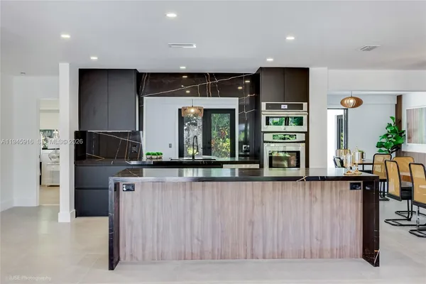 a kitchen with stainless steel appliances kitchen island granite countertop a refrigerator and a stove top oven
