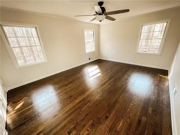a view of empty room with wooden floor and fan