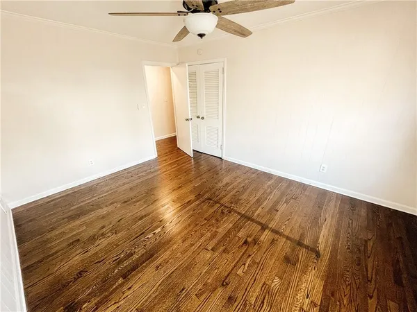 an empty room with wooden floor ceiling fan and window