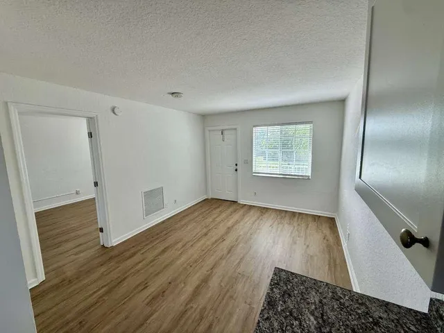 an empty room with wooden floor cabinet and windows