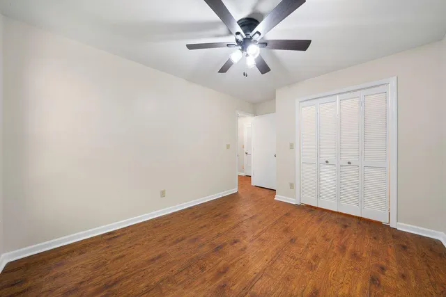 an empty room with wooden floor and fan