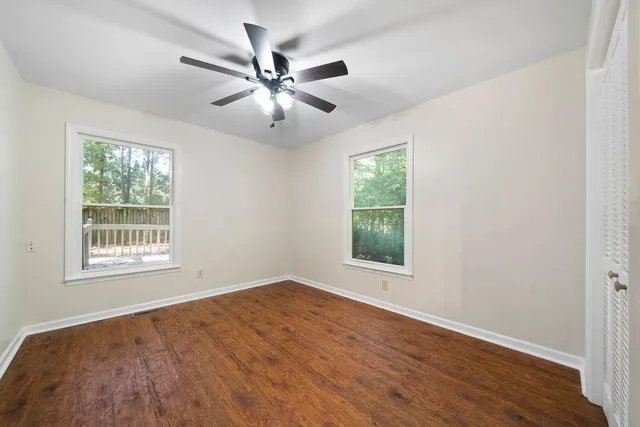a view of an empty room with wooden floor and a window