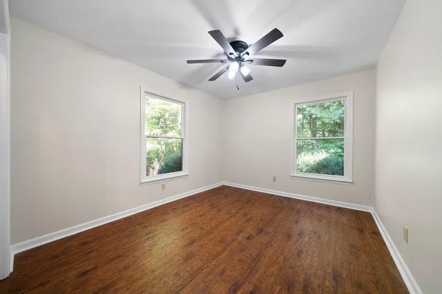 a view of an empty room with wooden floor and window