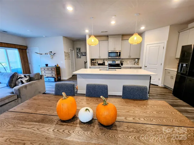 a large white kitchen with wooden floor and stainless steel appliances