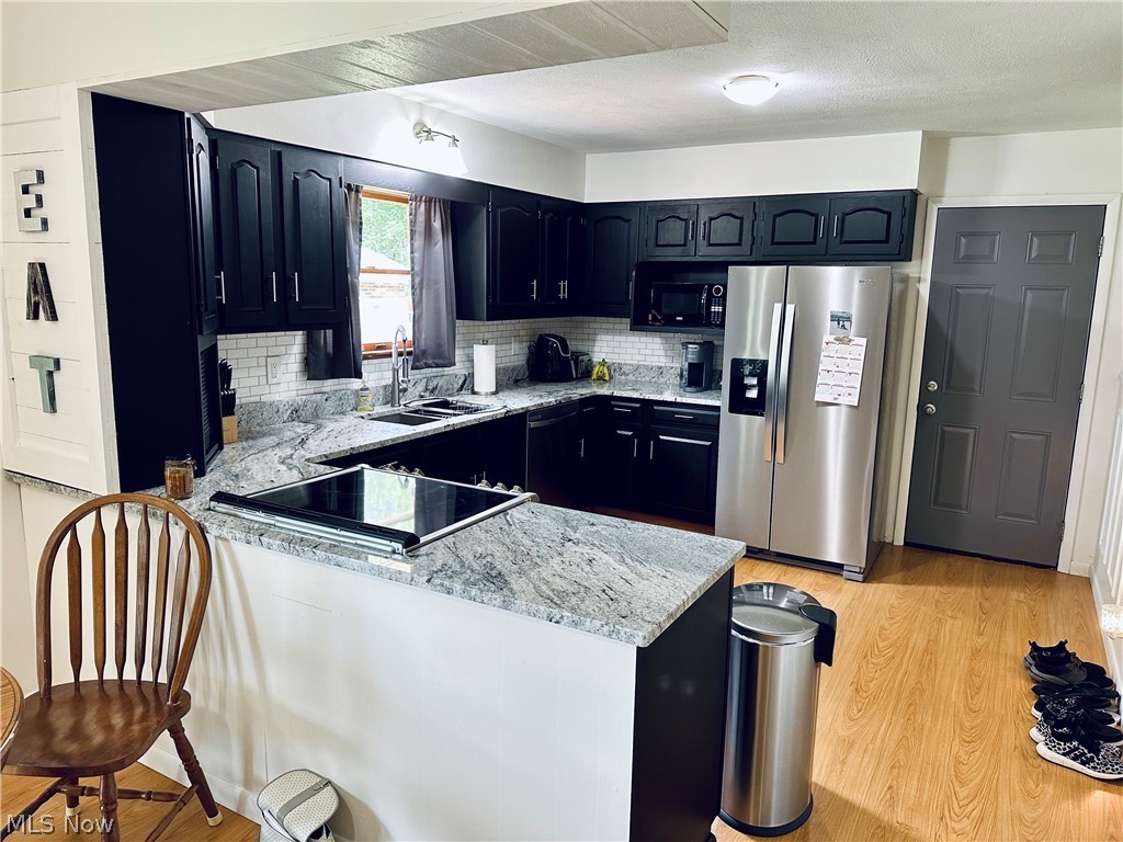 342 Taylors Ridge Road Henderson, WV 25106 - Photo 8 of 25 Kitchen with black appliances, decorative backsplash, sink, light hardwood / wood-style flooring, and kitchen peninsula